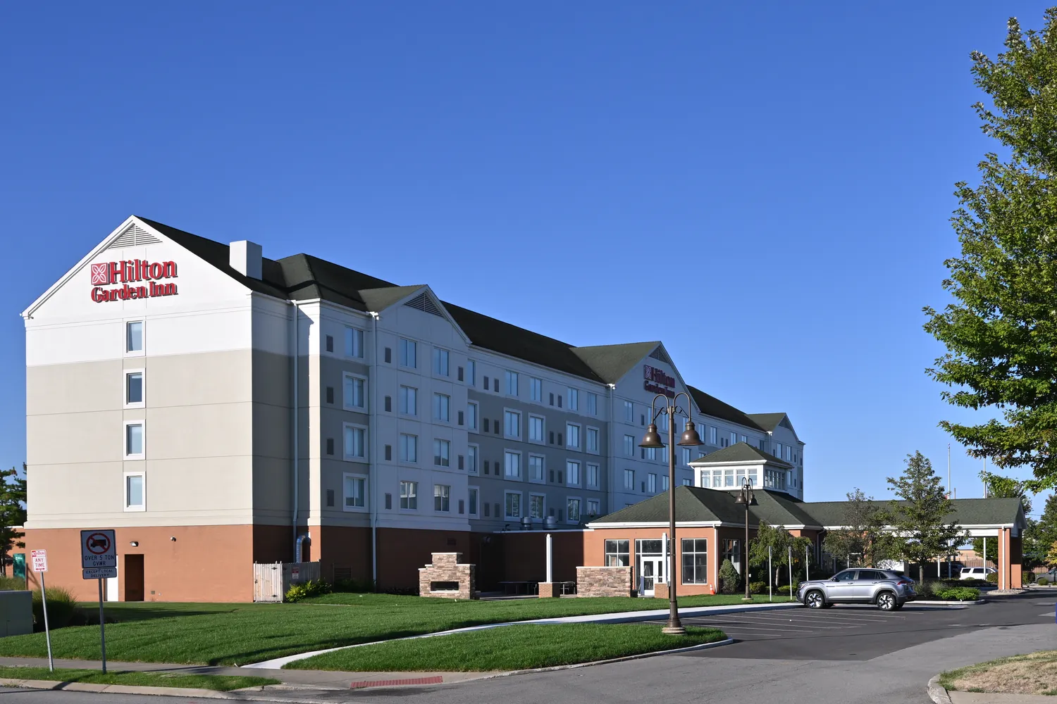Five-story select-service hotel with a covered entry and parking lot