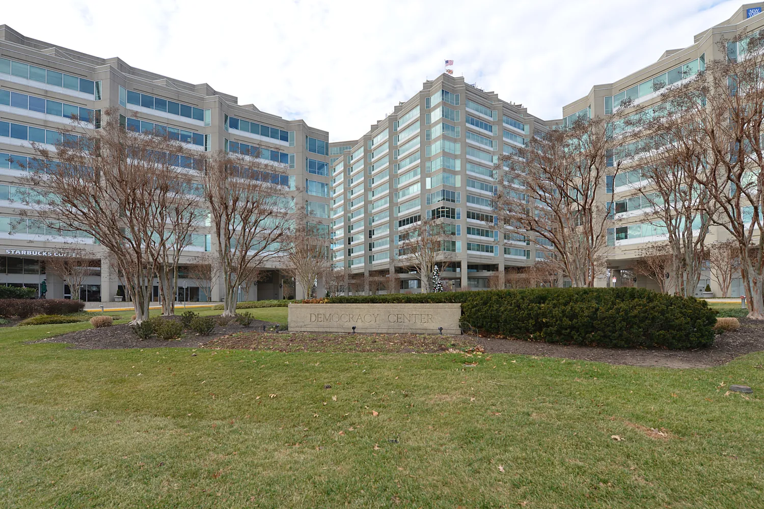 Multi-tenant office campus with glass-front towers behind a landscaped lawn
