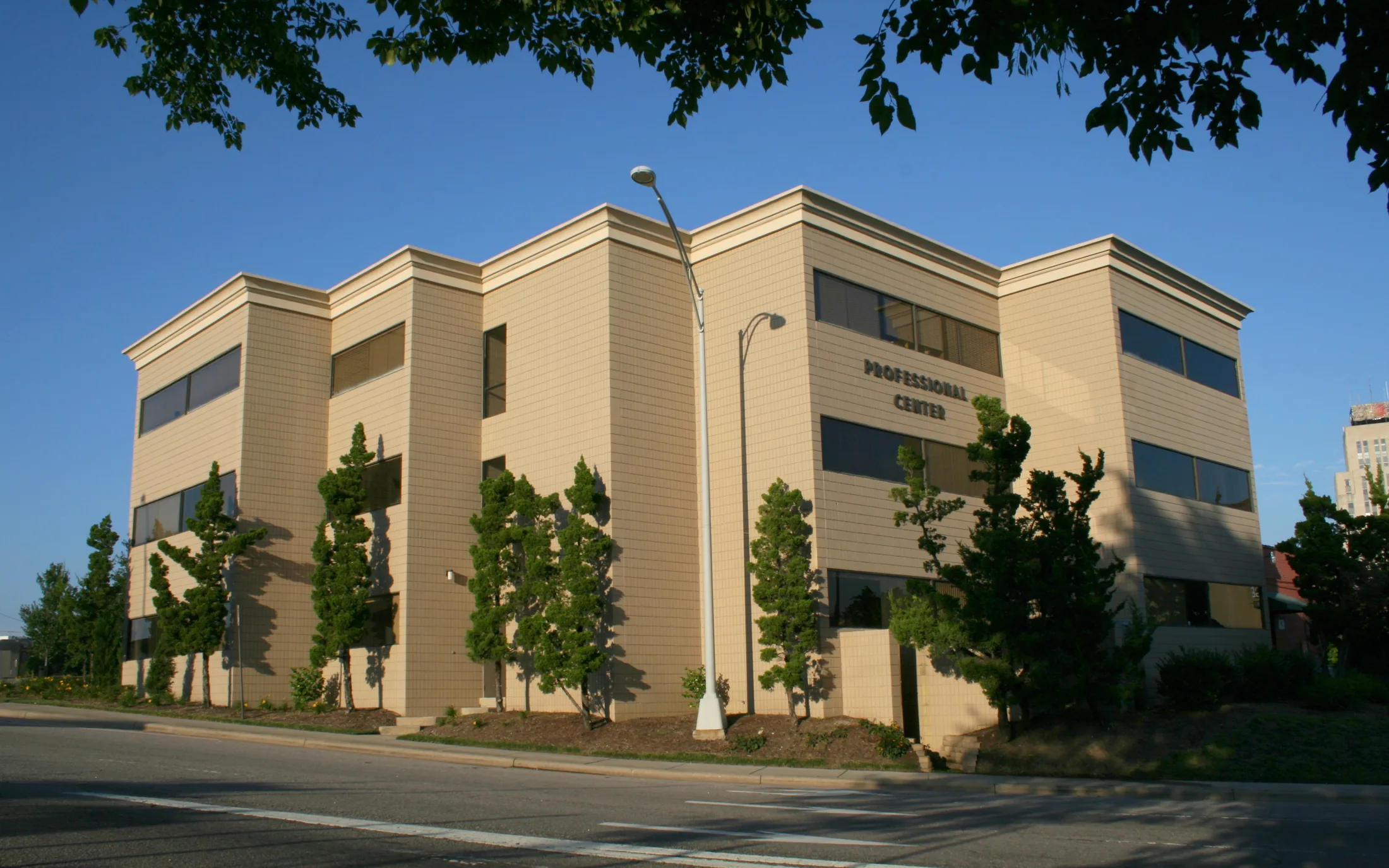 Two-story professional office building with trees along the street.